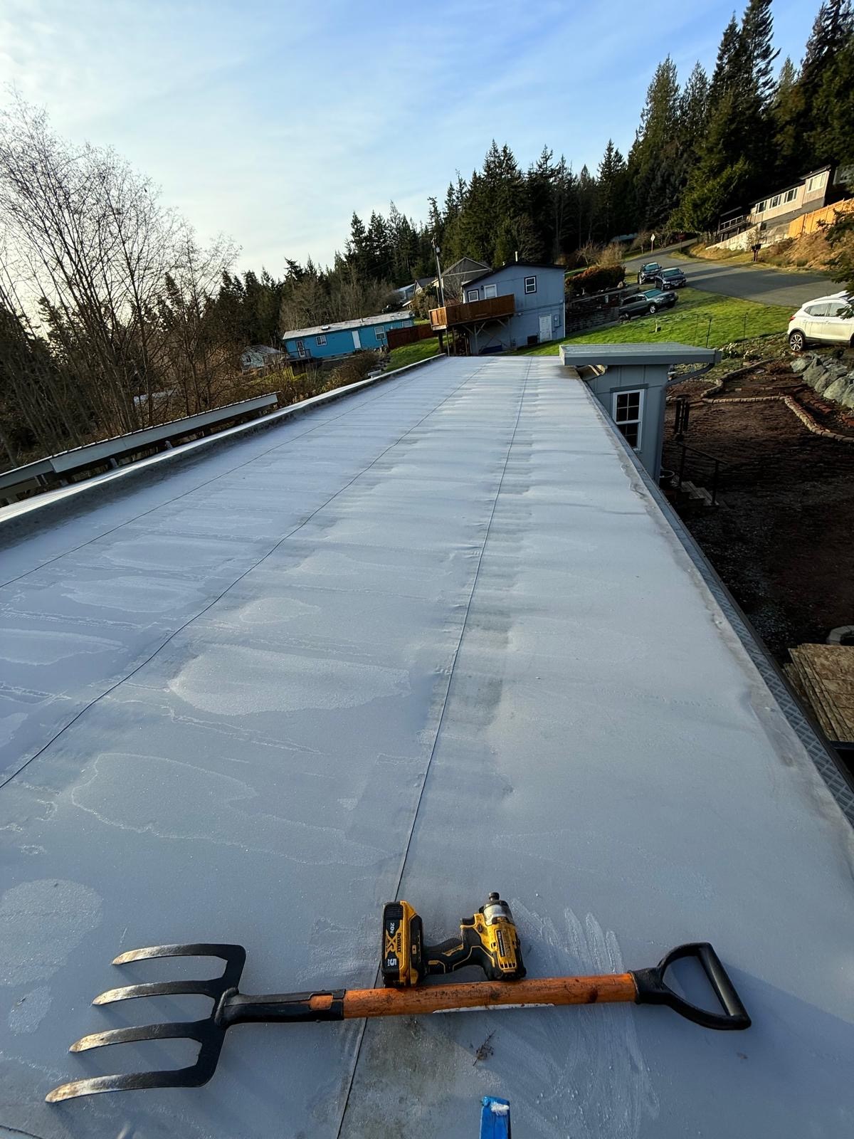 Existing low-slope TPO roof before replacement, with tear-off tools on the surface