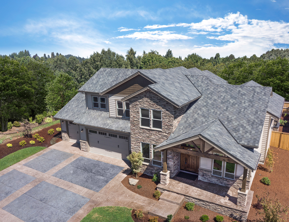 Malarkey manufacturer photograph of Windsor shingles in Storm Grey on a Salem, Oregon home surrounded by trees