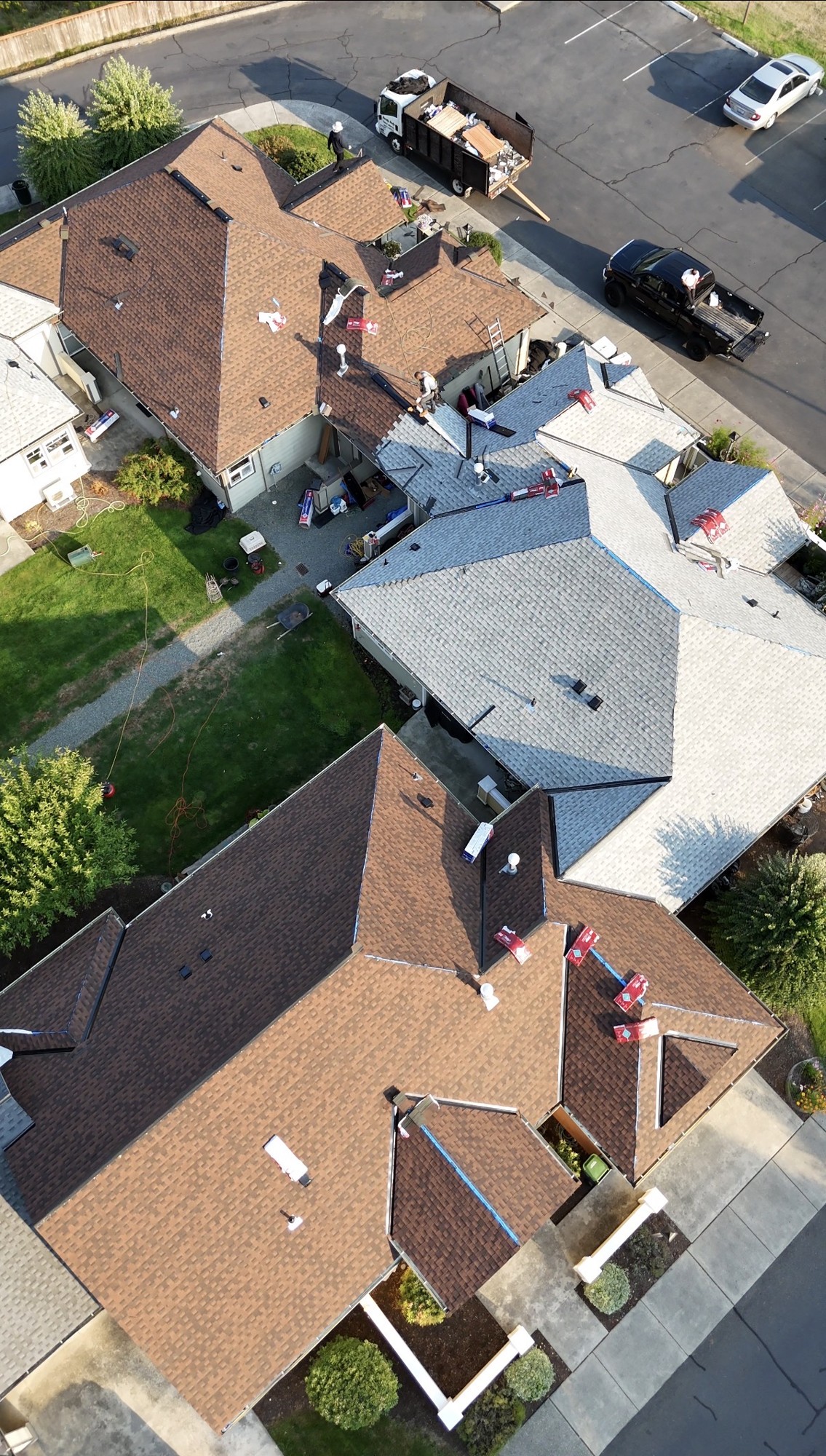 Overhead view of roofing work in progress with crew members and shingle bundles on Maple Ridge roofs