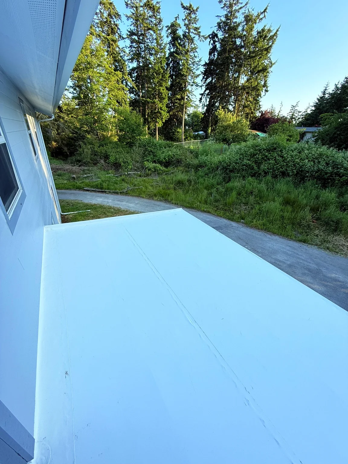 Finished white membrane roof beside the house wall overlooking the driveway
