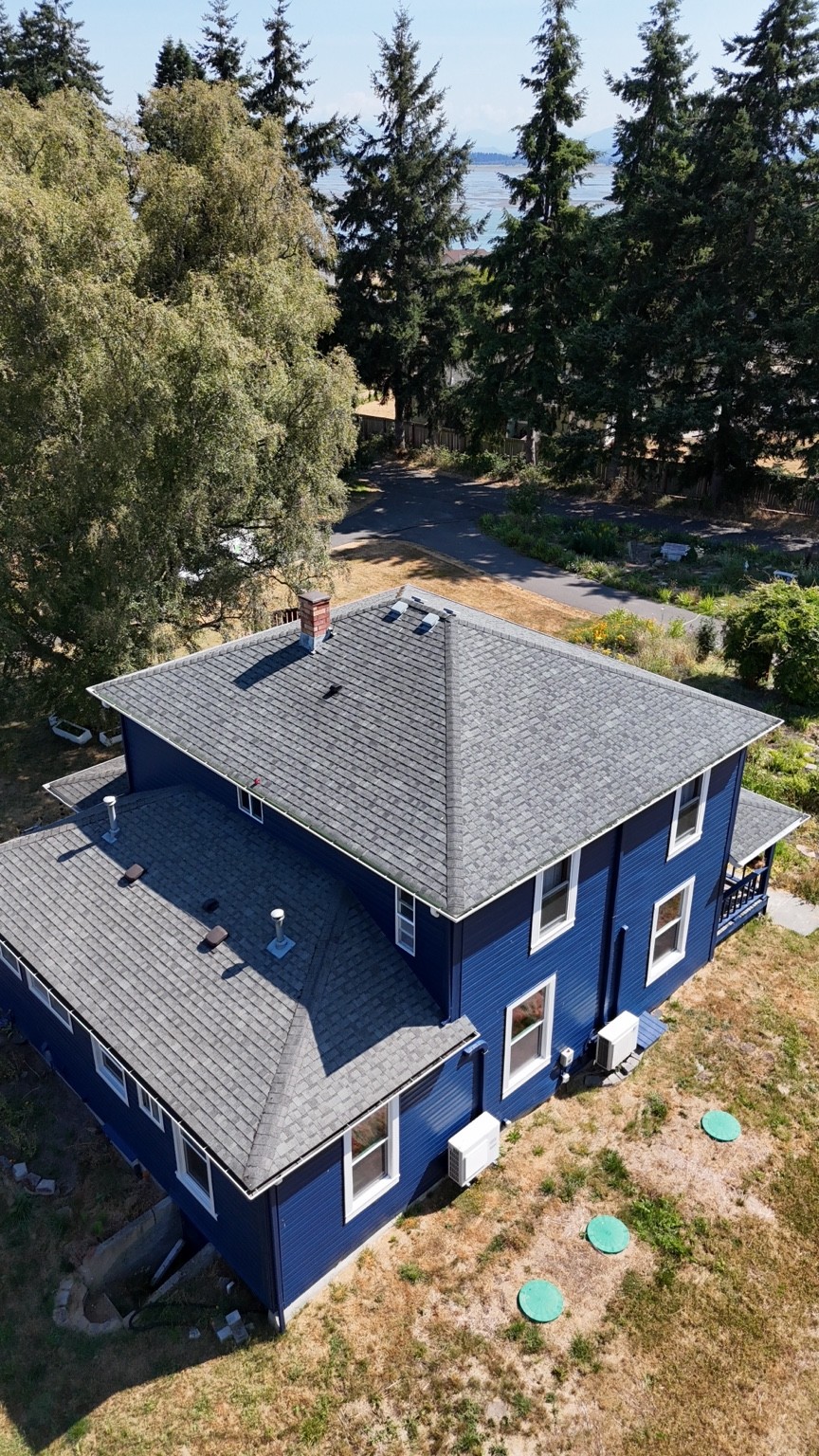 Before: gray asphalt shingle roof on a blue two-story home in Oak Harbor
