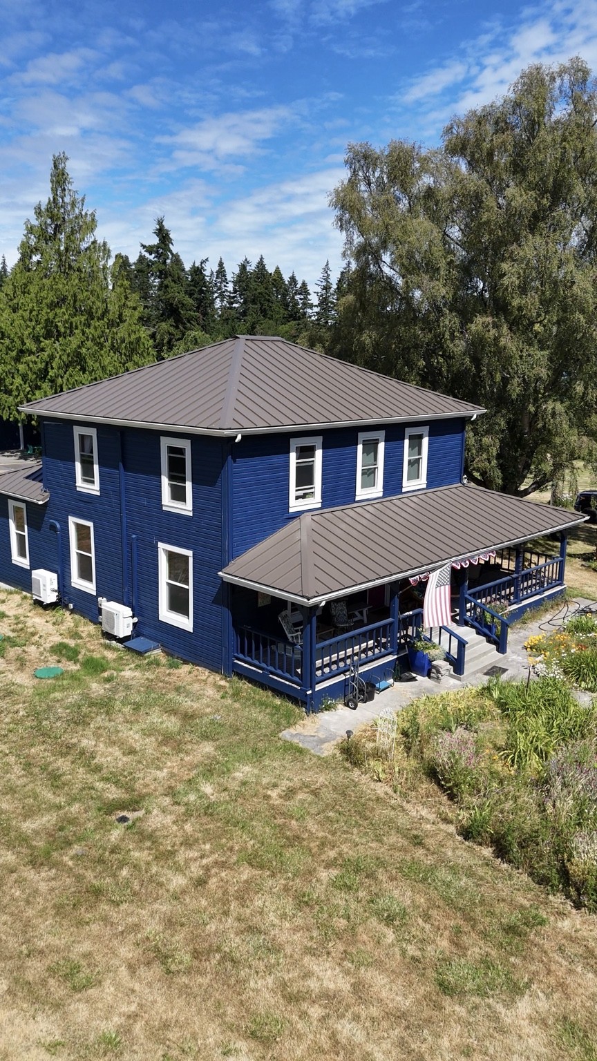After: Dark Bronze Nu-Ray NRM-1000 standing seam roof on the blue Oak Harbor home and its porch