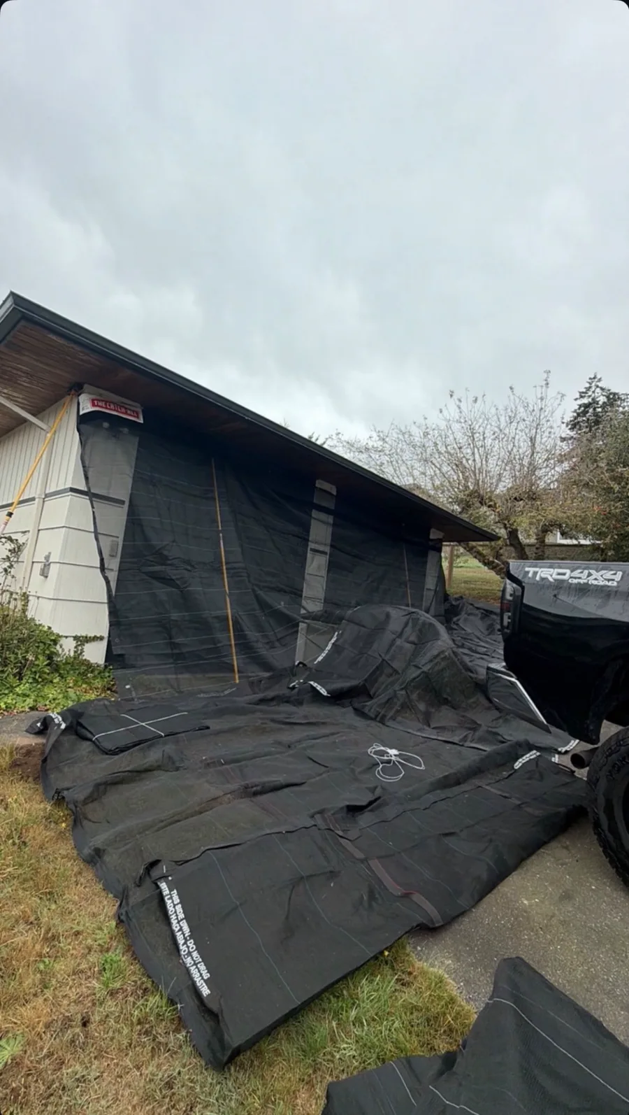 Catch-All netting and ground covers protecting siding and areas around a home before roofing work