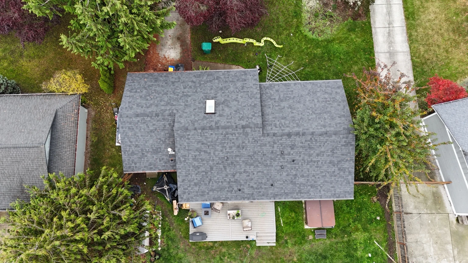 Top-down photograph of the completed Midnight Black shingle roof and skylight on the Rockridge home