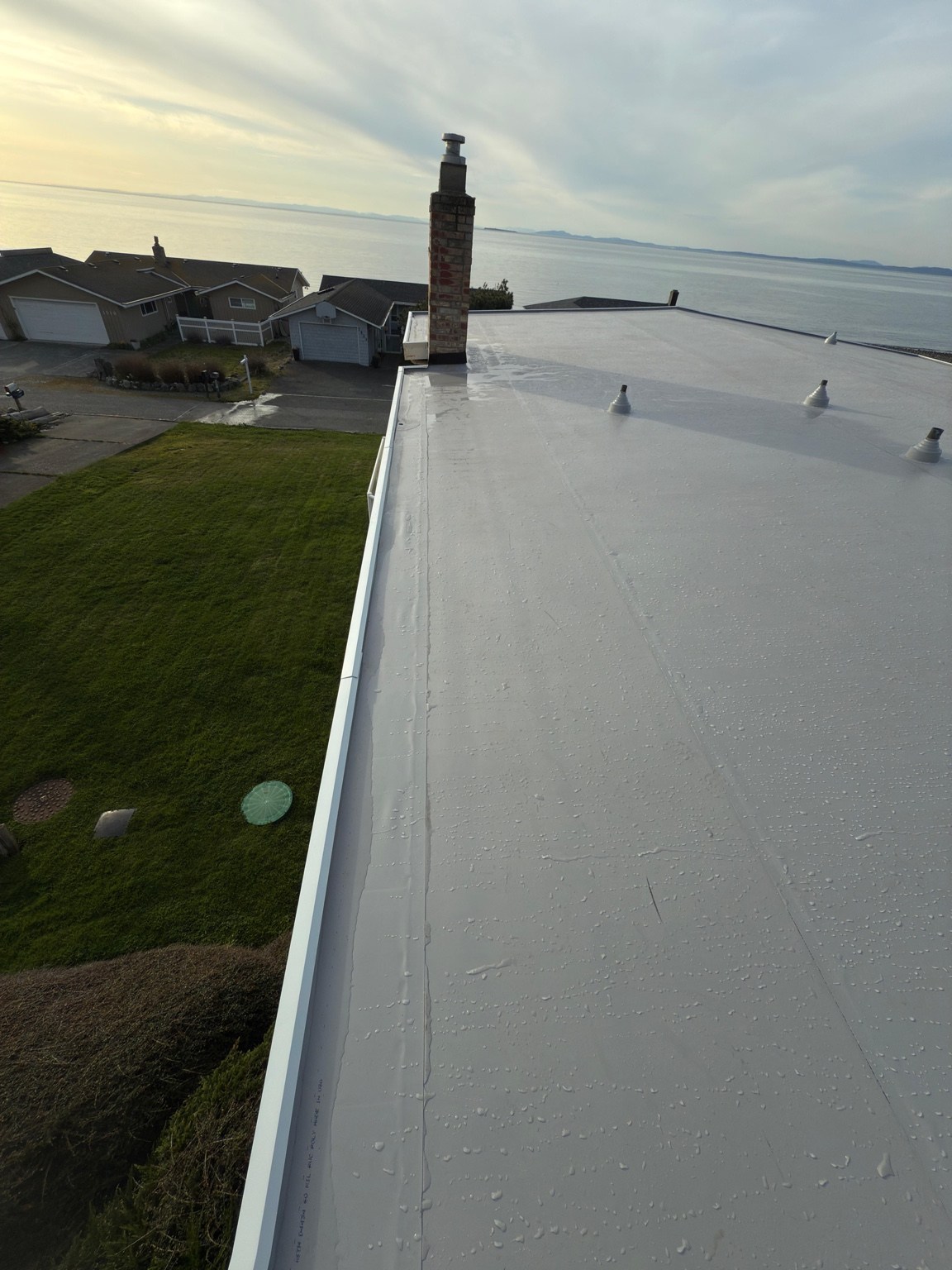 Gray PVC roof and new perimeter flashing beside the lawn at the West Beach home