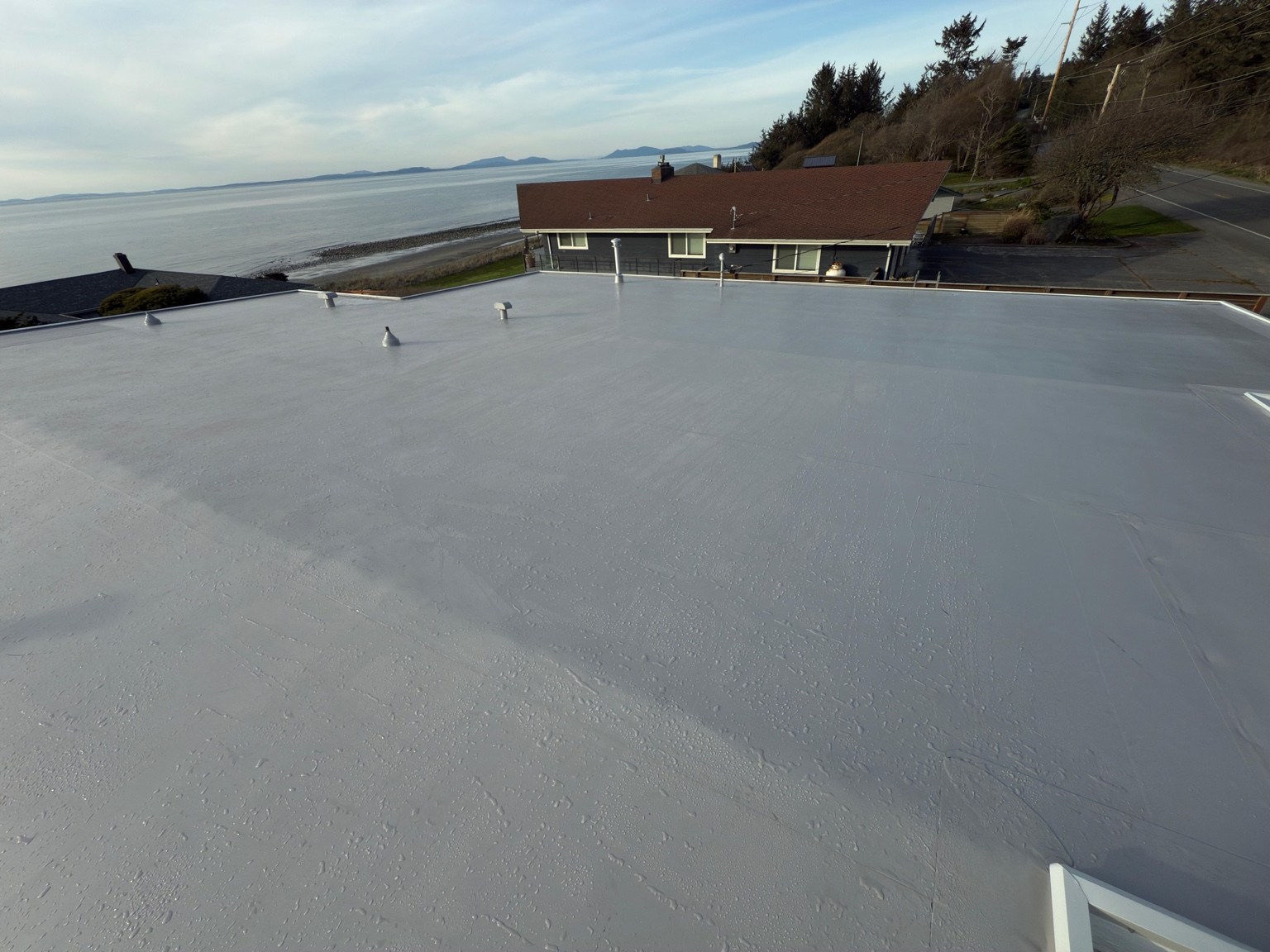 Completed gray PVC roof at West Beach in Oak Harbor with the shoreline beyond