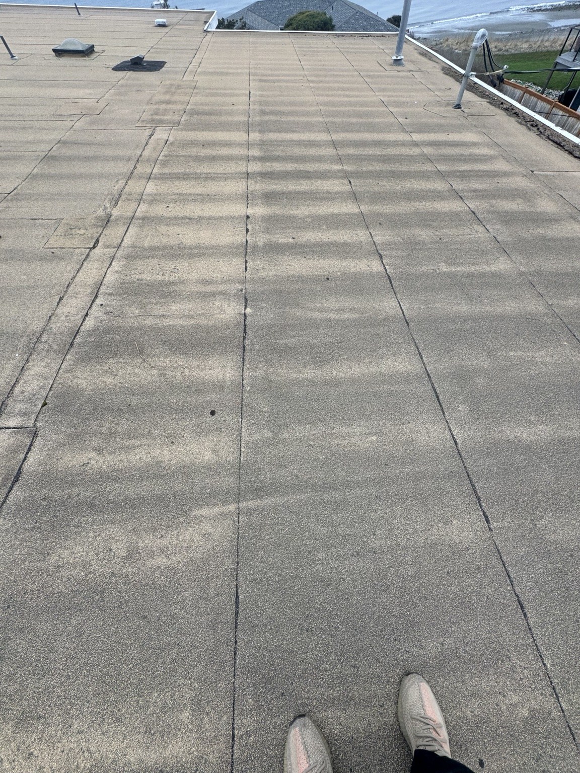 Existing weathered low-slope roof before replacement at the West Beach home