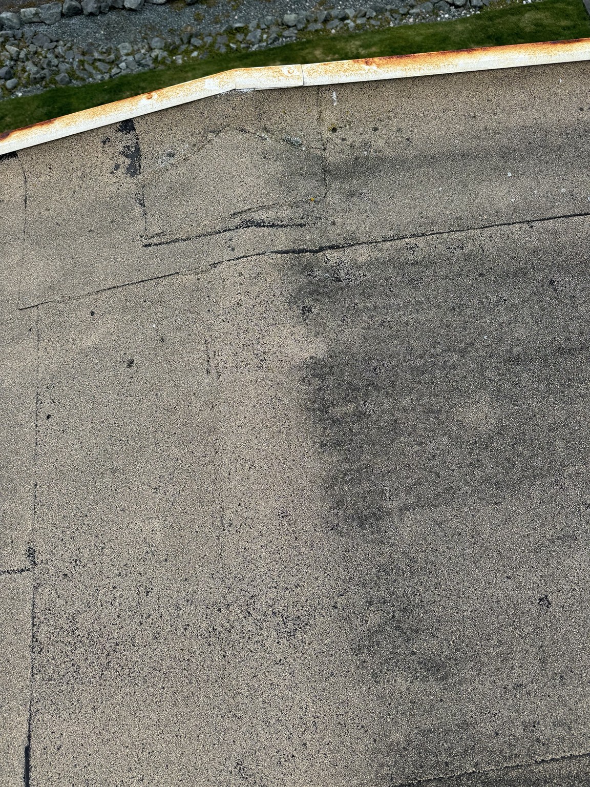 Close view of worn roof seams and rusted perimeter metal before replacement